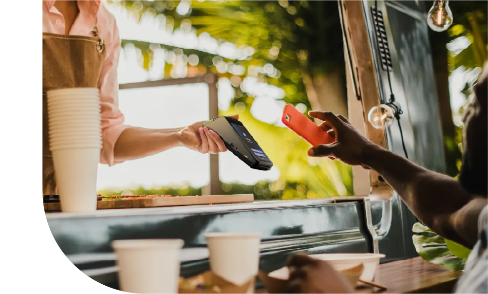 Verkäuferin an einem Food Truck nimmt eine kontaktlose Zahlung per Smartphone entgegen